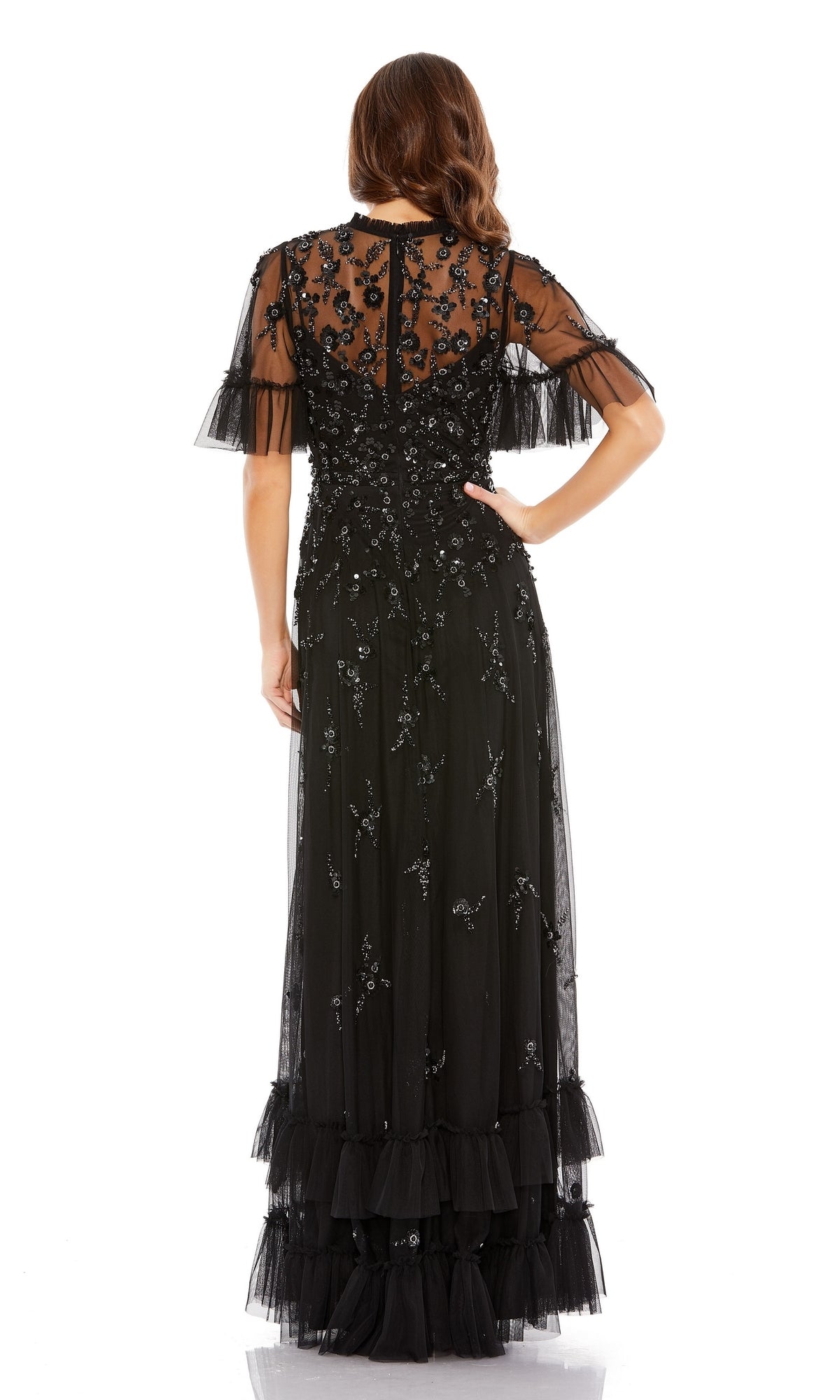 A woman is shown from the back wearing the Mac Duggal 9199 Short Sleeve Beaded Formal Gown featuring beaded embellishments and layered tulle detailing at the hem.